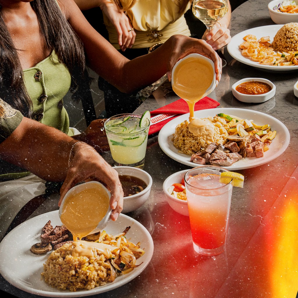 hibachi fried rice, grilled chicken, and sautéed mixed vegetables, all arranged on a white plate. A bowl of colorful cabbage salad and a pair of wooden chopsticks are set on the dark table.
